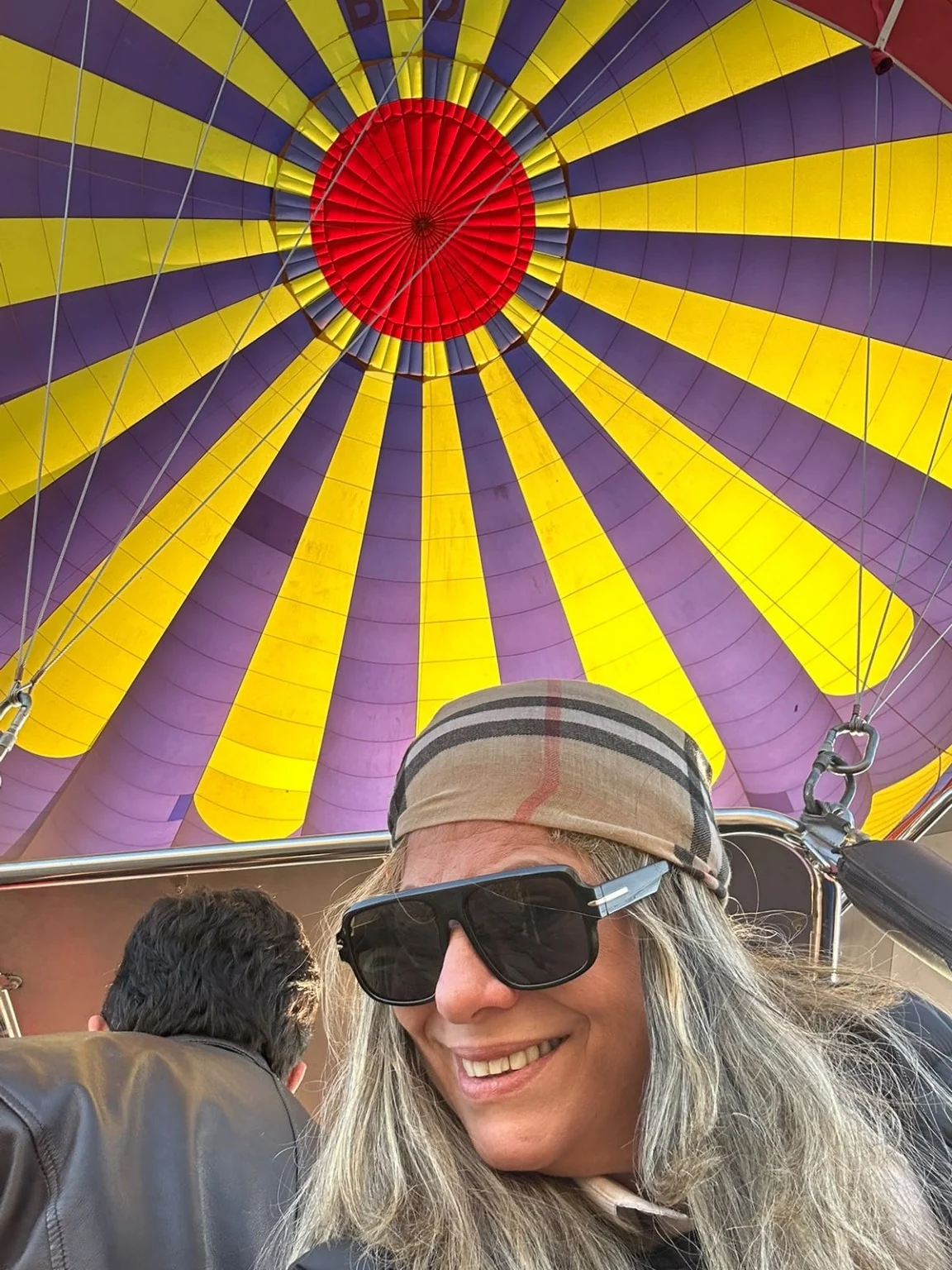 Colorful hot air balloon canopy above travelers in Cappadocia